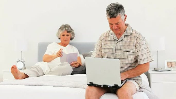 妻子读书时，男人在笔记本电脑上工作