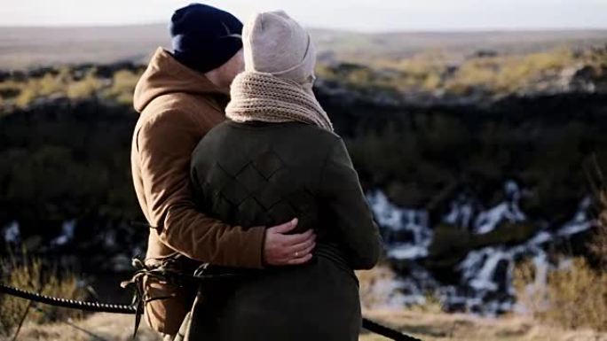 年轻美丽的夫妇在冰岛巴纳福斯瀑布附近的悬崖上搁浅，欣赏美景