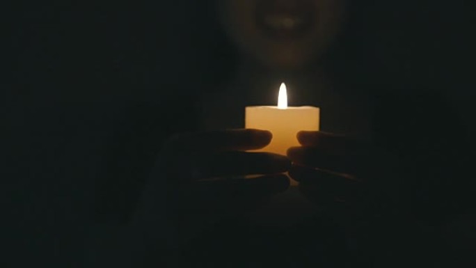 在黑暗中拿着点燃的蜡烛