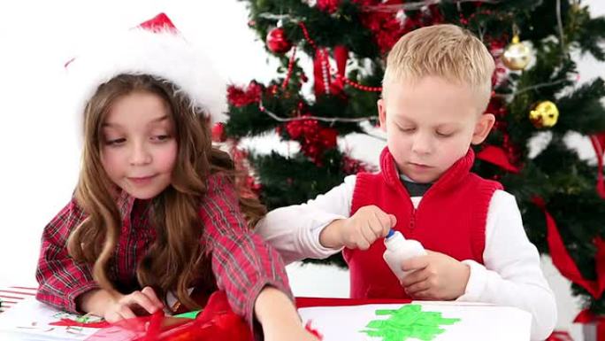 可爱的兄弟姐妹在圣诞树旁制作艺术品