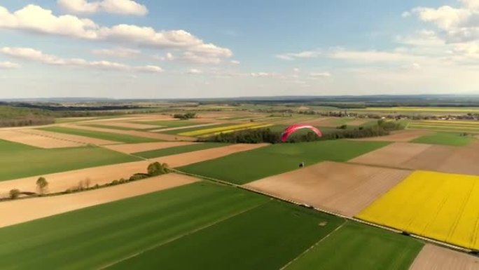 空中无人机视角滑翔伞，带降落伞，实时覆盖阳光明媚的乡村景观