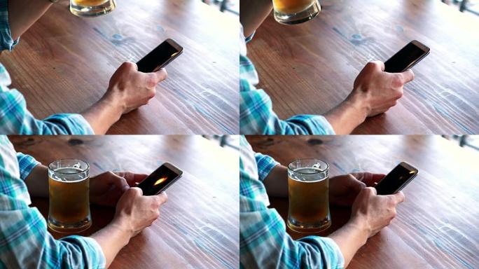 男人在喝啤酒时使用手机