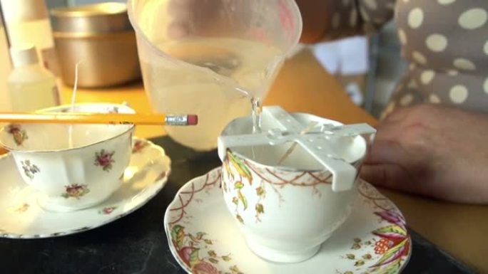 女人在家中在茶杯中制作蜡烛的慢动作镜头