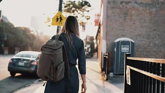 夏天，背着背包的年轻时尚女性在日落时独自行走，在市中心消磨时光