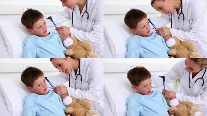 医生检查坐在床上的生病男孩的耳朵