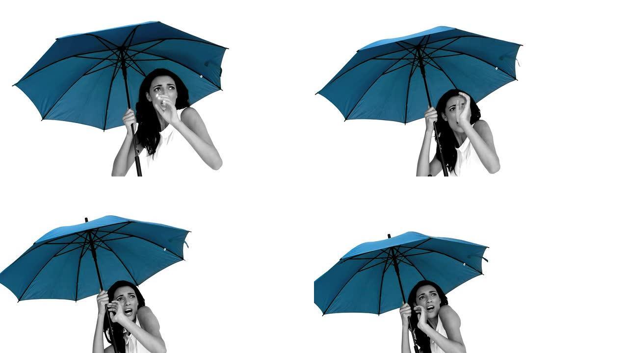 蓝色雨伞下的女人因恐惧而畏缩