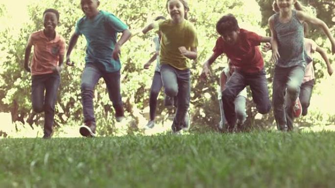 可爱的小学生在外面的草地上赛跑
