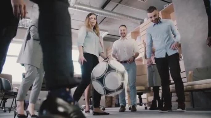 年轻的办公室员工在休息时踢足球。临时工享受健康的职场氛围慢动作