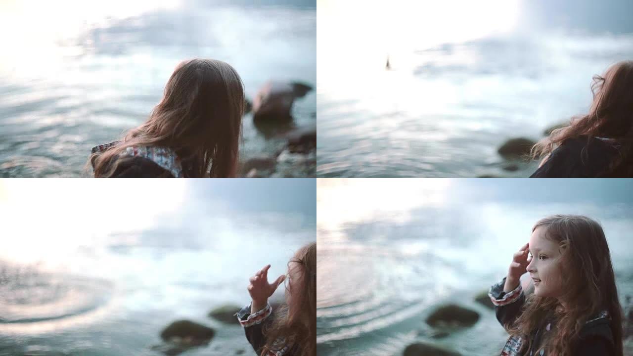 可爱的小女孩站在靠水的岸边，向水中扔石头