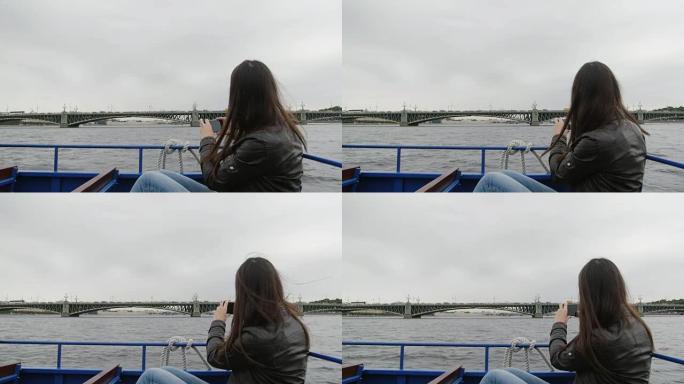 黑发女人在圣彼得堡的一座桥拍照。她坐在一辆河边的公共汽车上，风吹着她的头发，慢慢地