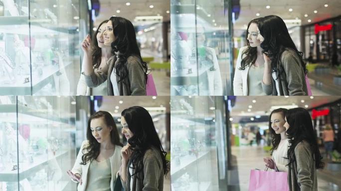 两个女孩正在看购物中心珠宝店的橱窗。手持镜头。