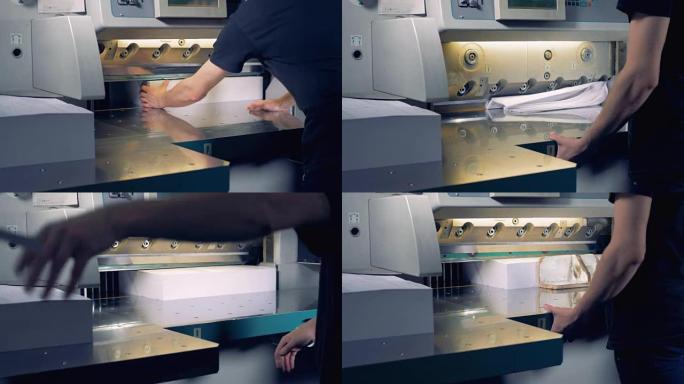 印刷厂工人操作切割机。工人在排版中切割一叠纸。