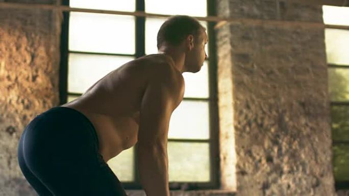 肌肉赤裸的男人吃力地举起沉重的杠铃。他在工业健身房做排长排的弯腰健身操。