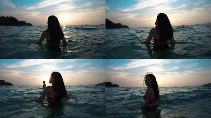 穿着比基尼的亚洲性感女孩，头发和嘴唇湿湿，在海上的日落中嬉戏