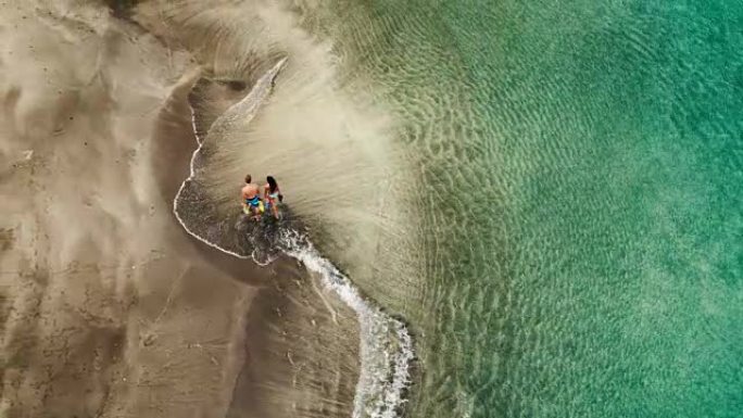 度假在热带海滩上散步的年轻夫妇的鸟瞰图