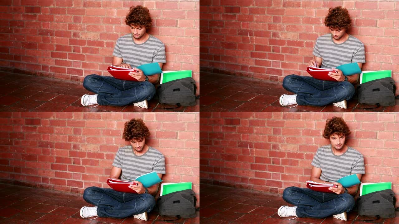 学生坐在墙上阅读教科书