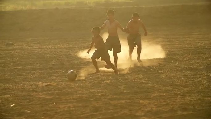 乡村儿童的慢动作在一个村庄的阳光下踢足球。