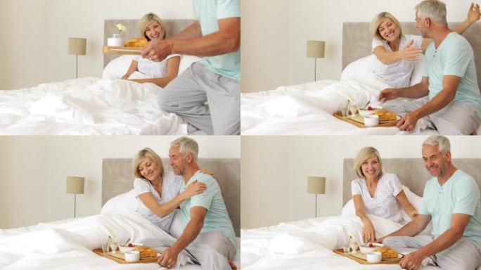 浪漫的丈夫带他快乐的妻子在床上吃早餐