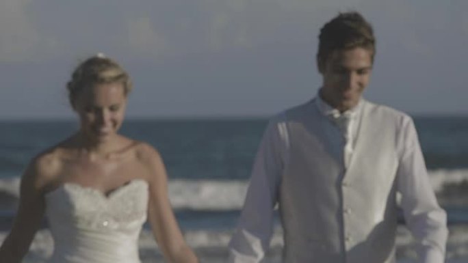 微笑的新婚夫妇在沙滩上奔跑