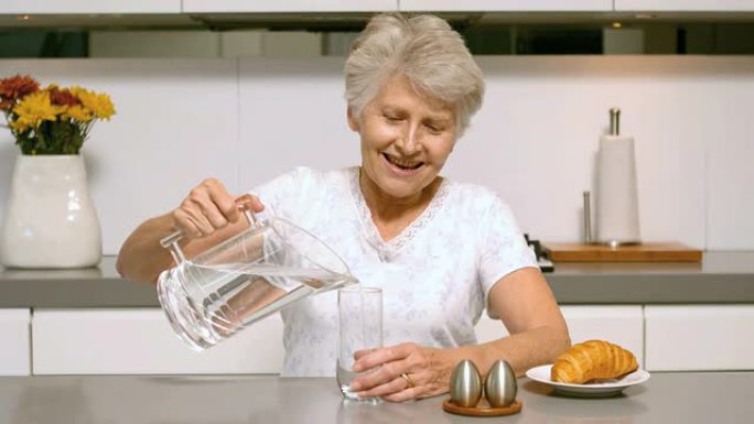 退休妇女倒杯水作为早餐