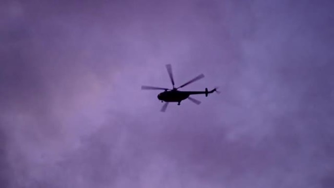 直升机在树梢上方飞行。黄昏