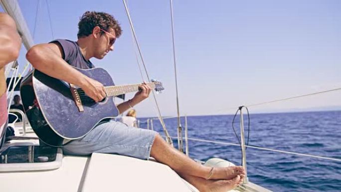 男人放松，在阳光明媚的帆船上弹吉他，实时