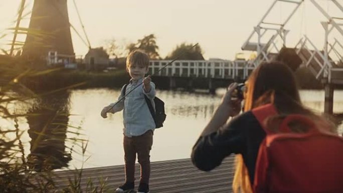 母亲拍了一个男孩玩海盗的照片。日落湖码头的家庭娱乐时间。旧风车。小演员。4K