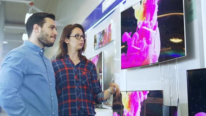 年轻夫妇在电子商店购买新的4k电视机。他们试图决定最好的模式，但有疑问。