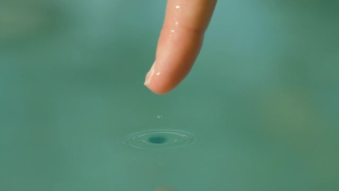 慢动作: 小水滴从女人的指尖滑入游泳池。