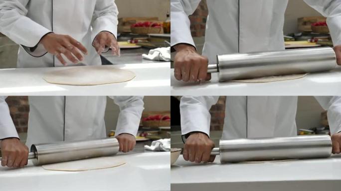 无法识别的厨师使用金属rolling面杖制作比萨饼的特写镜头