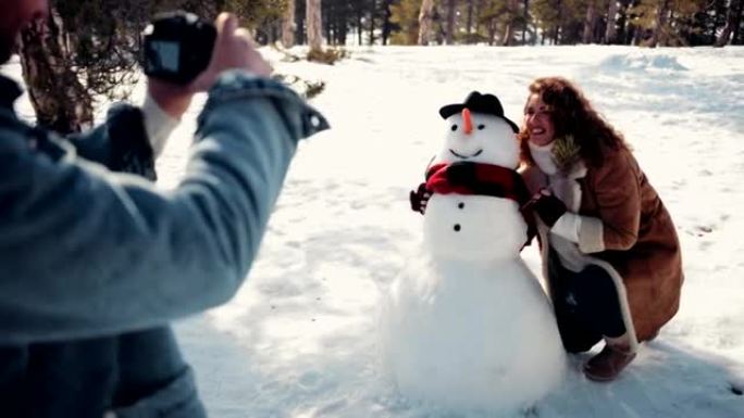 情侣在雪地里和雪人合影很开心