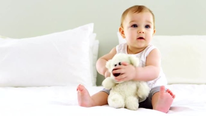 可爱的女婴在床上玩毛绒玩具