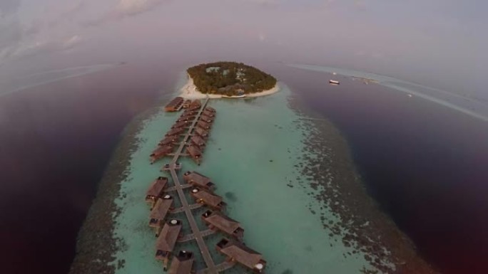 马尔代夫热带岛屿度假胜地海上日落和豪华水上别墅的鸟瞰图。