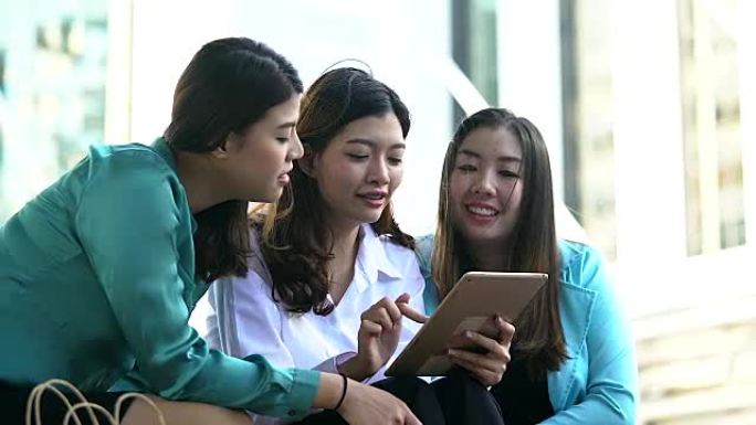 一群军官妇女与他们的朋友一起使用智能手机在网上购物。年轻的亚洲女性使用智能手机上网查找数据信息或在线