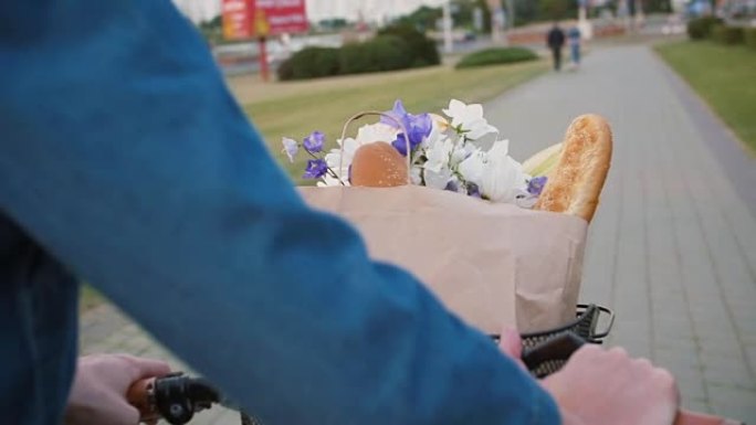 女人在街上行走时，把手放在自行车车把上，篮子里放着鲜花和面包，缓慢的mo，steadicam射击