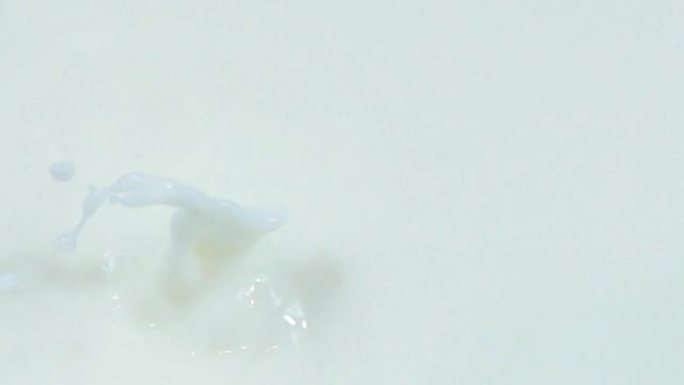一个蔓越莓在慢动作中与酸奶一起掉入牛奶中