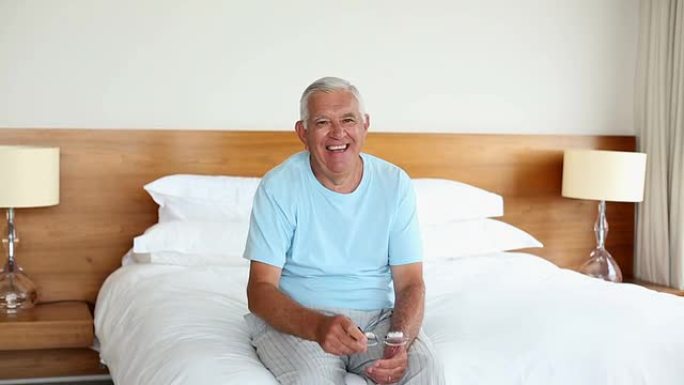 早上坐在床上的老人对着镜头微笑