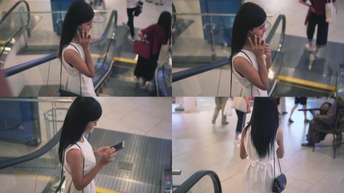 在购物中心的自动扶梯上使用智能手机的女人