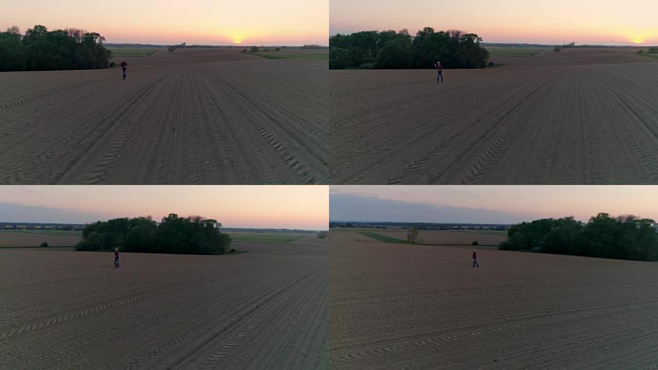 WS鸟瞰图农民在日落时分在田园诗般的农村耕地中撒播种子