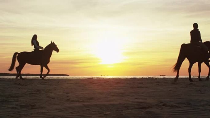日落灯光下海滩上两个骑马的人的剪影。