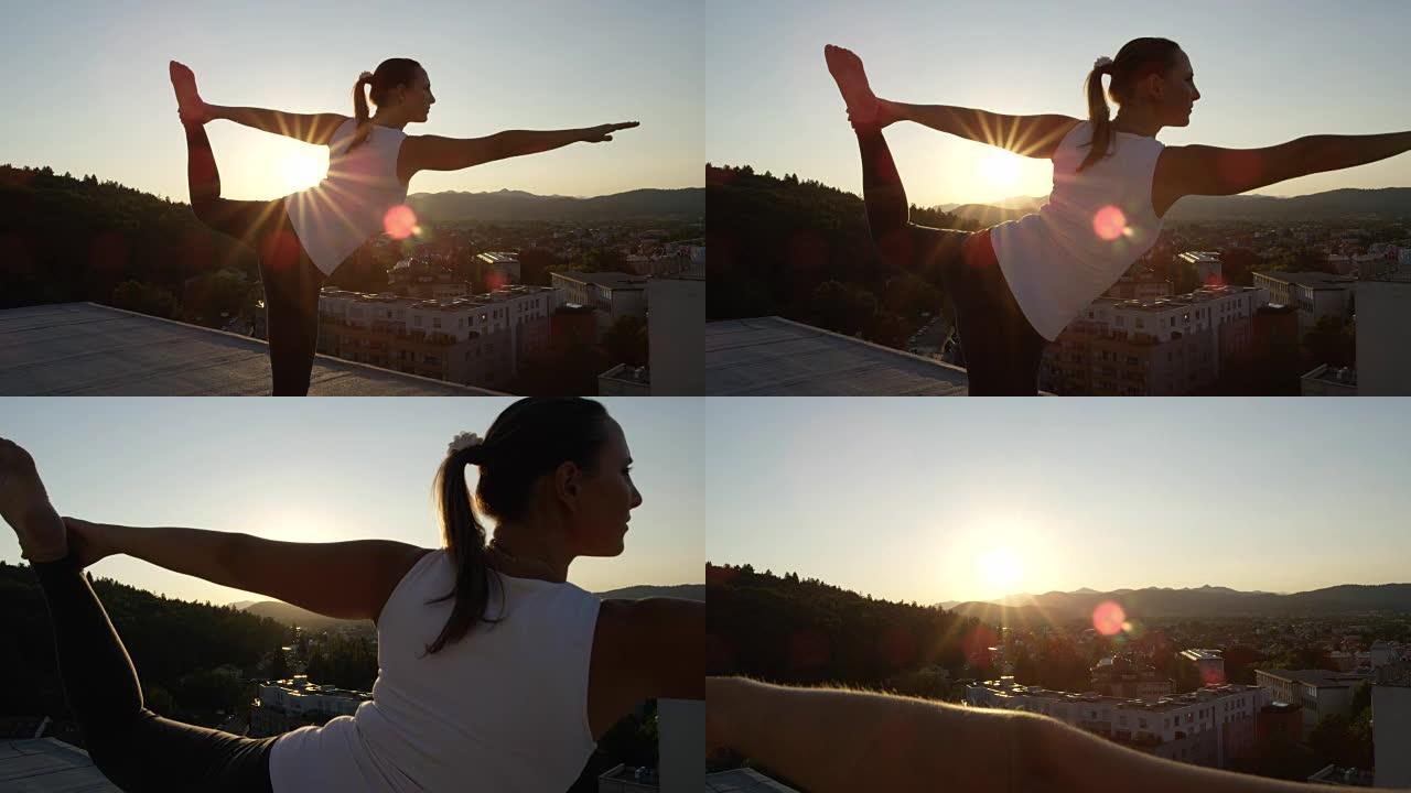 特写: 强大的女孩在日落时在屋顶上做舞蹈瑜伽的姿势
