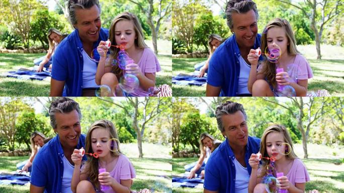 父亲和女儿在公园4k野餐时用泡泡棒吹泡泡