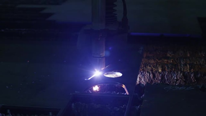 一台数控等离子切割机的特写镜头，该切割机正在一家重工业工厂切割金属物体。