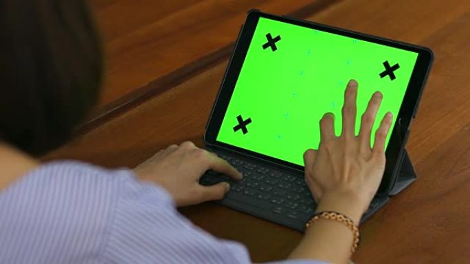 一名亚洲妇女在带有绿色钥匙的笔记本电脑上打字的肩膀镜头。
