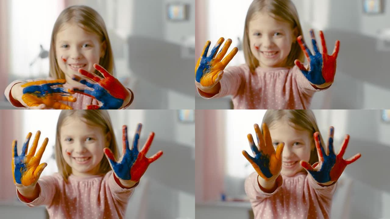 可爱的微笑女孩展示她的双手被彩色油漆覆盖。