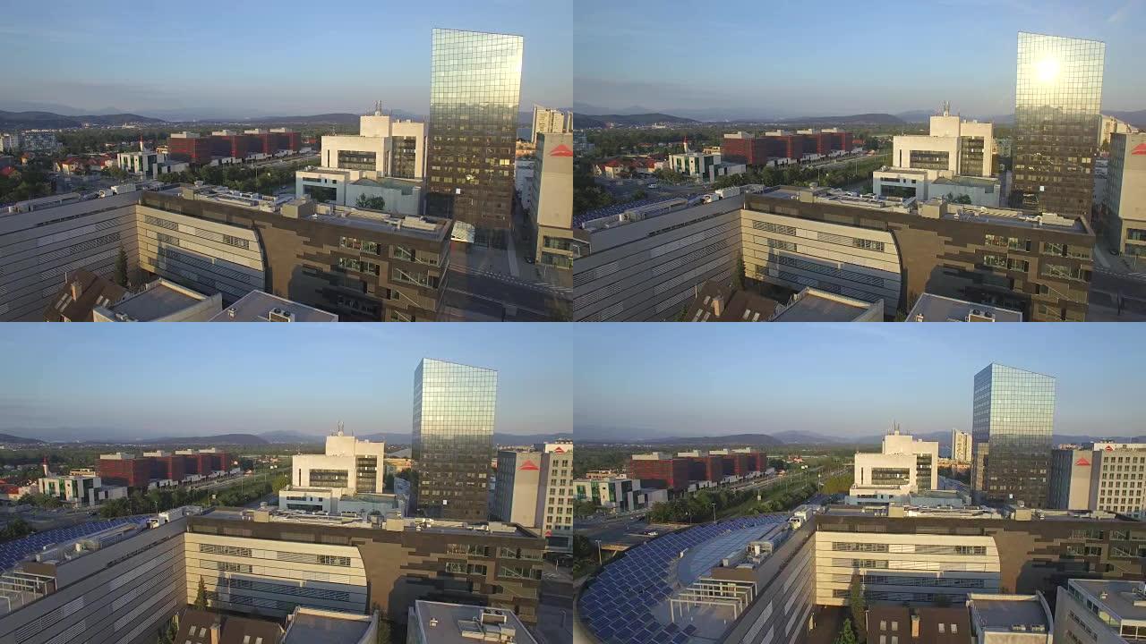 空中: 在商业区上空飞行，早晨的阳光在日出时映入市中心的高高的玻璃摩天大楼中
