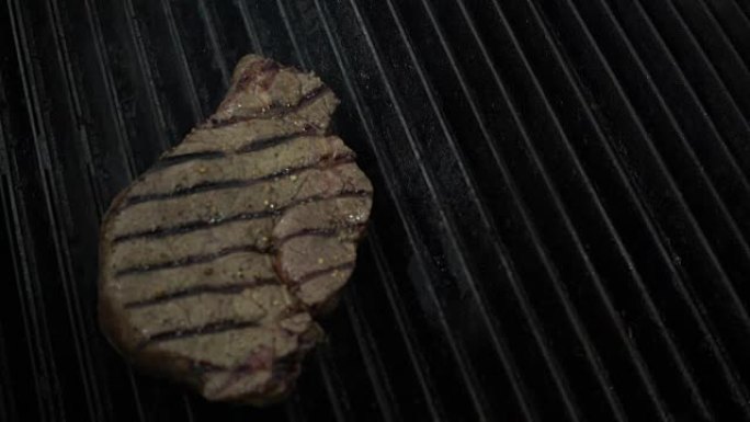 烹饪主任使用金属镊子将未煮熟的肉块放在热烟熏烤架上，并在下面放火，关闭慢动作。