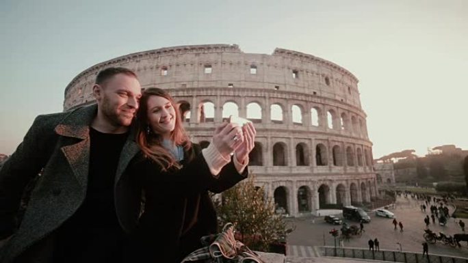幸福的年轻夫妇在意大利罗马竞技场附近自拍。旅行的男人和女人在镜头前微笑