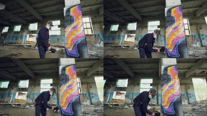 城市街头艺术家正在用肮脏的墙壁和窗户在废弃的建筑中涂鸦，他正在使用喷漆。现代艺术品和创造性的人的概念