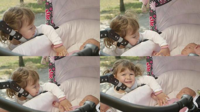 特写:好奇的姐姐看着可爱的小妹妹躺在婴儿车里。